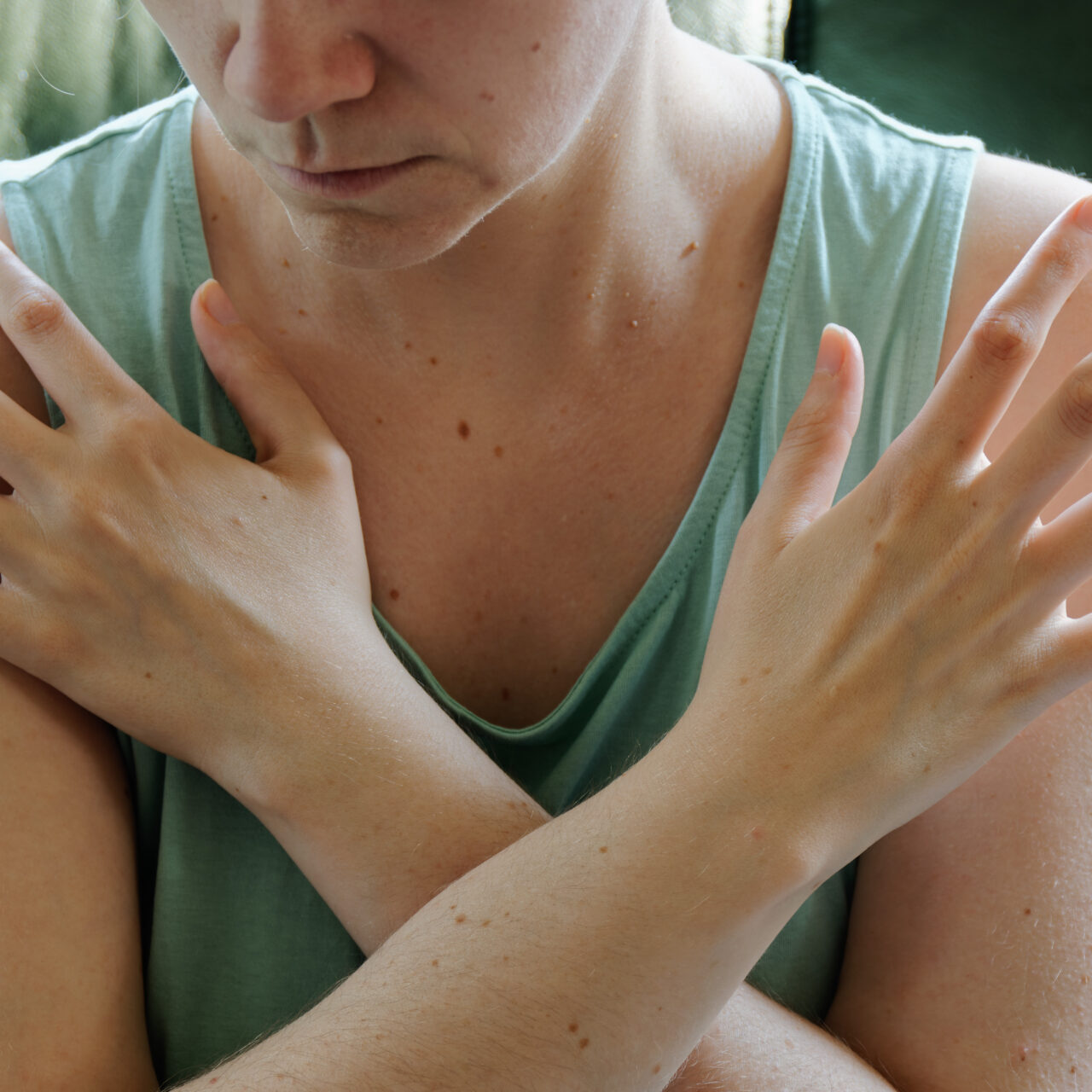 Woman tapping her shoulders, crossing hands. Butterfly hug self-care technique.