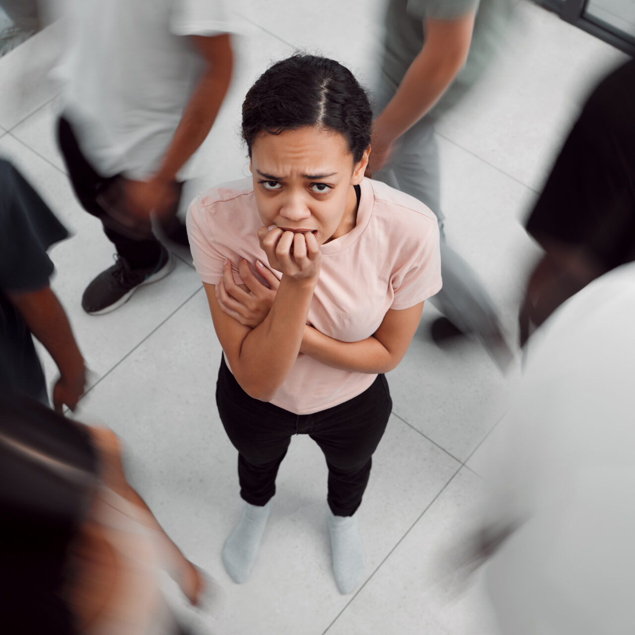 Shot of a young woman experiencing mental illness while being surrounded by people inside.