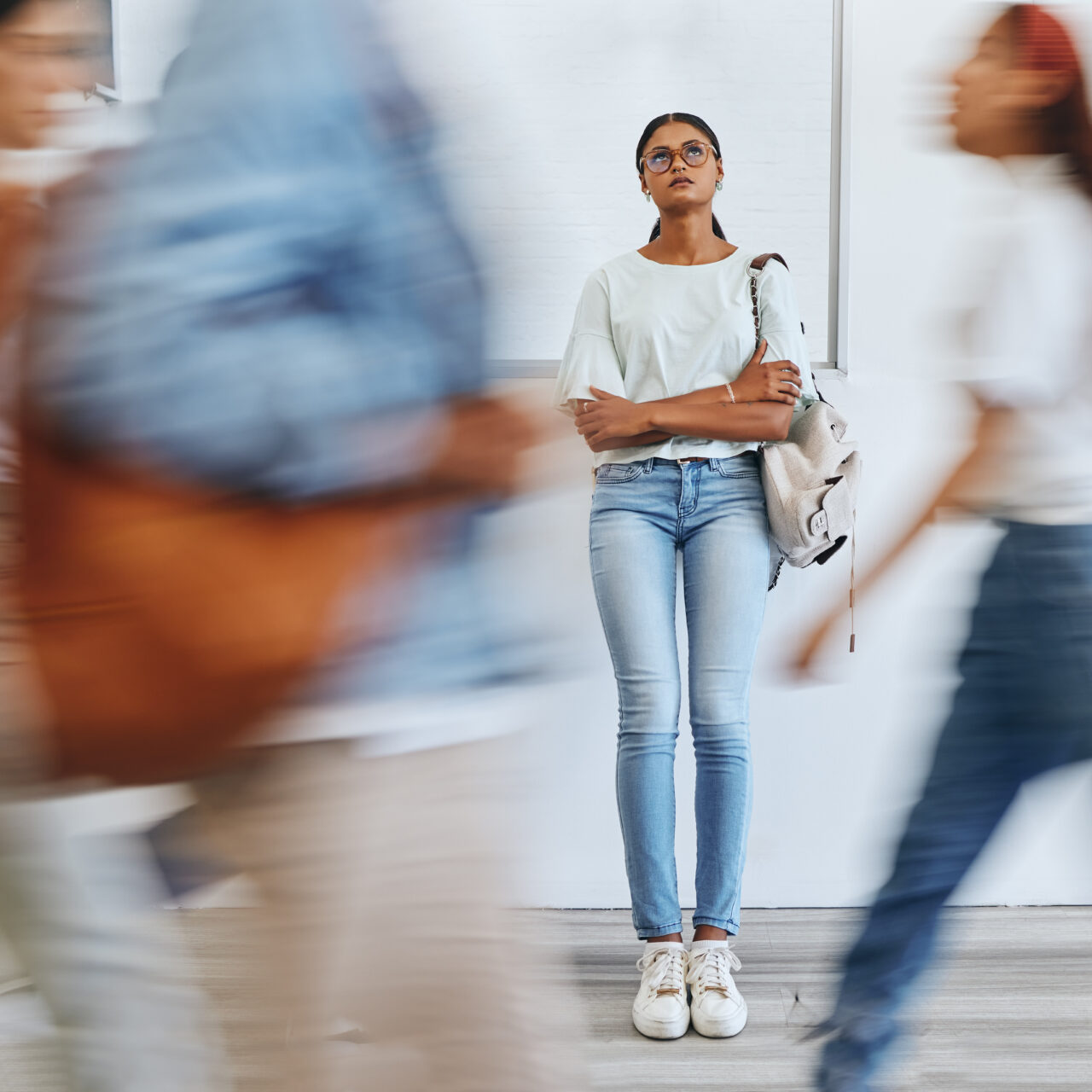 Woman in busy crowded university corridor, sad and thinking. Stress, anxiety and depression, studen.